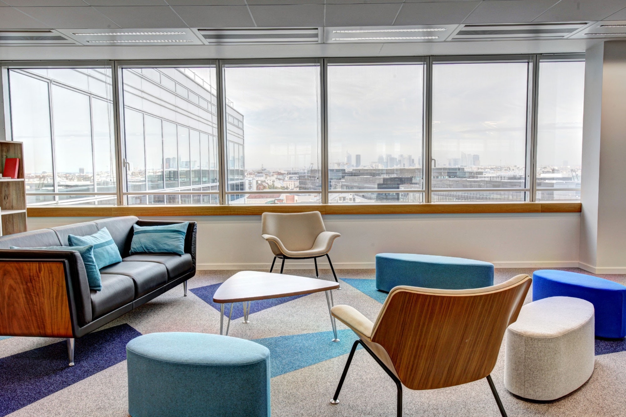 empty chairs arrayed around a modern coffee table in a vacant conference room with a city view through windows in the background